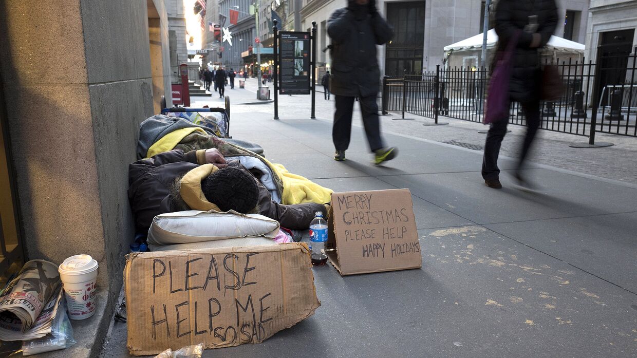 Бездомный спит на Уолл-стрит возле нью-йоркской фондовой биржи