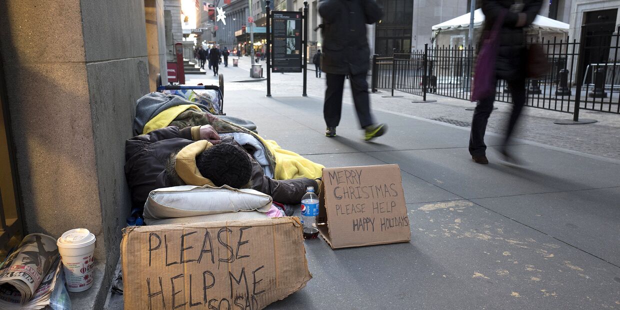 Бездомный спит на Уолл-стрит возле нью-йоркской фондовой биржи