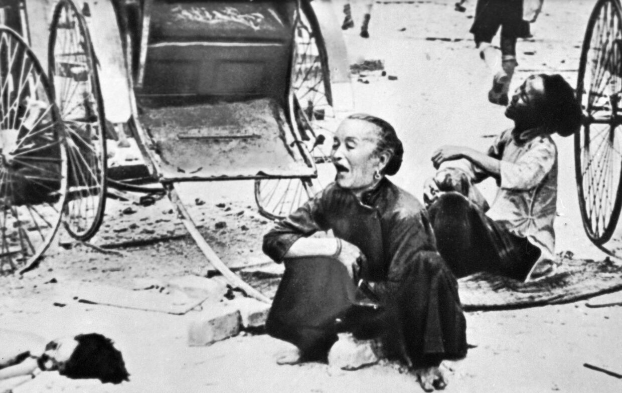 Убитая горем малазийка плачет над телом ребенка (справа) после японской бомбардировки 13 марта 1942 года во время одного из последних рейдов перед захватом Сингапура японцами.