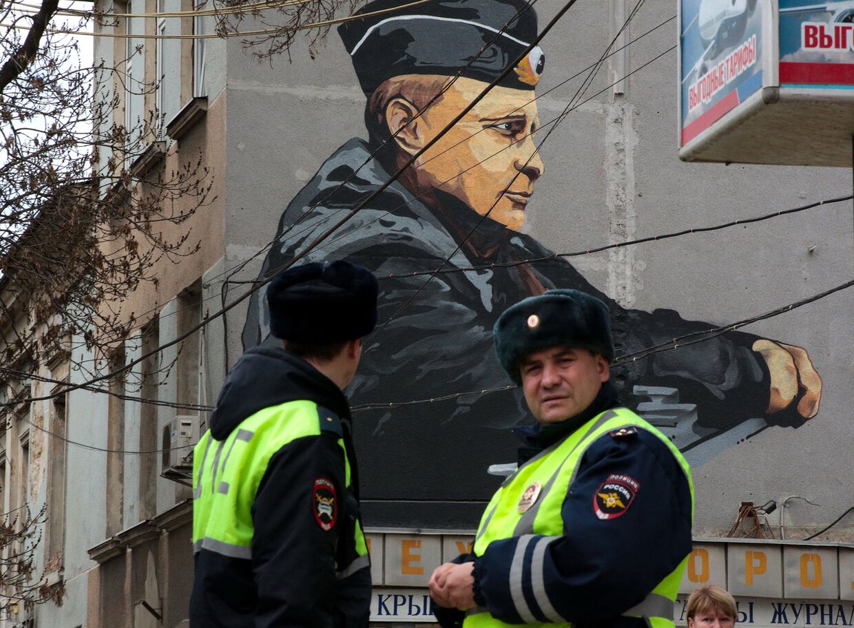Сотрудники ДПС на фоне граффити с изображением президента России Владимира Путина в Симферополе