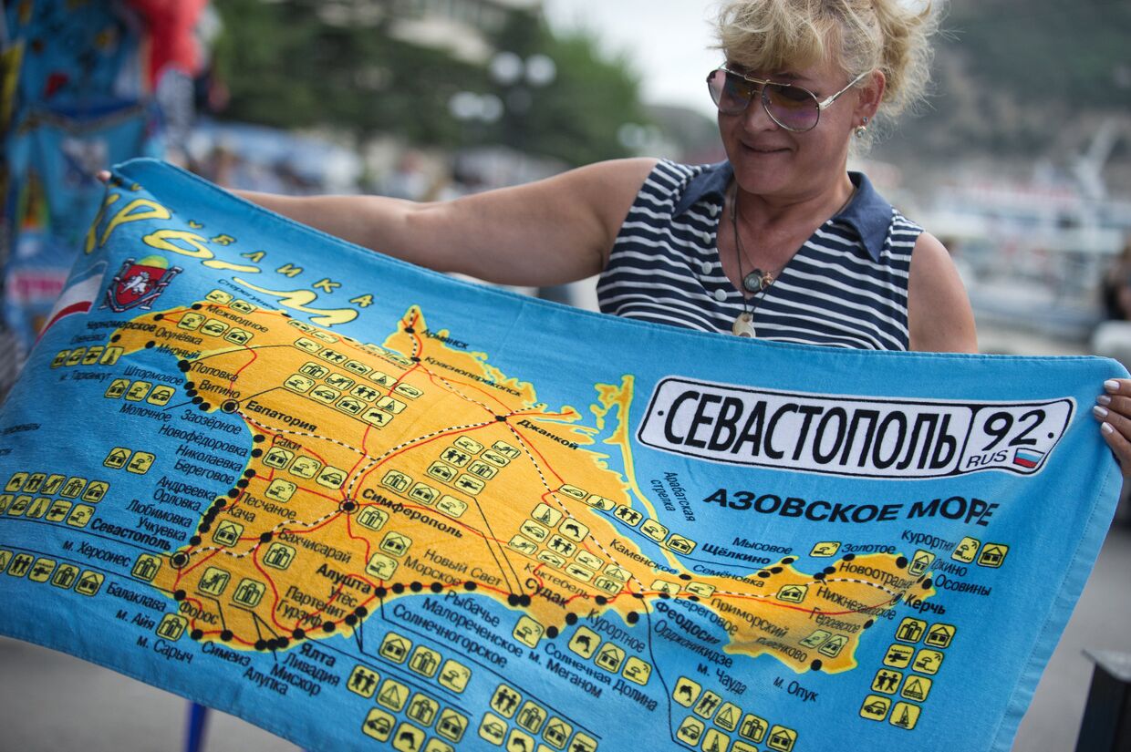 Женщина рассматривает пляжное полотенце с картой Крыма