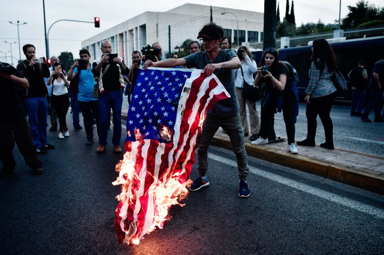 Сожжение флага США перед зданием посольства Сша в  Афинах в Греции. 14 апреля 2018