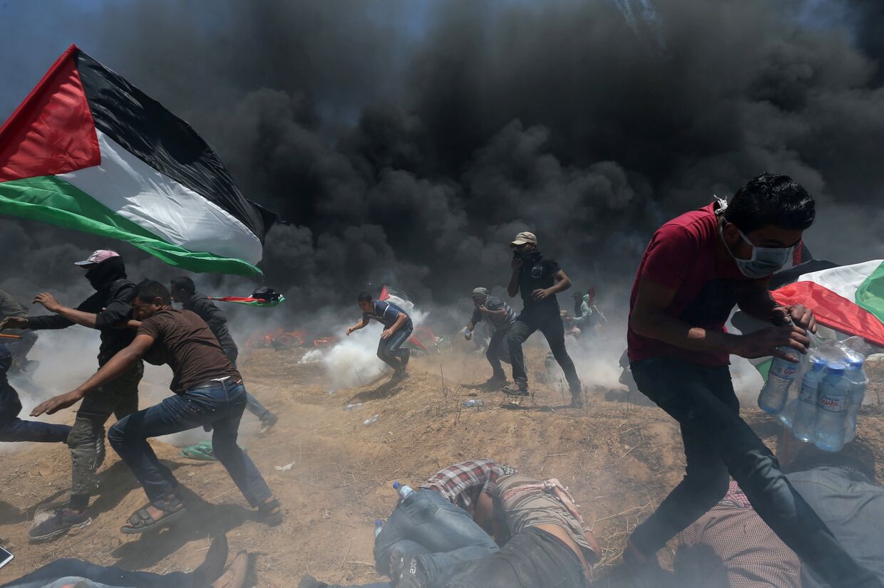 Палестинские демонстранты убегают от слезоточивого газа во время акции протеста против переноса посольства США в Иерусалим
