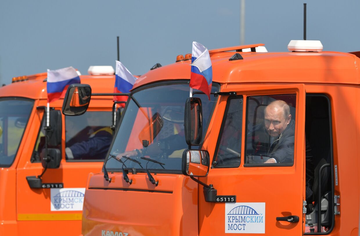 Президент РФ Владимир Путин садится за руль автомобиля Камаз во время проезда колонны строительной техники по автодорожной части Крымского моста. 15 мая 2018