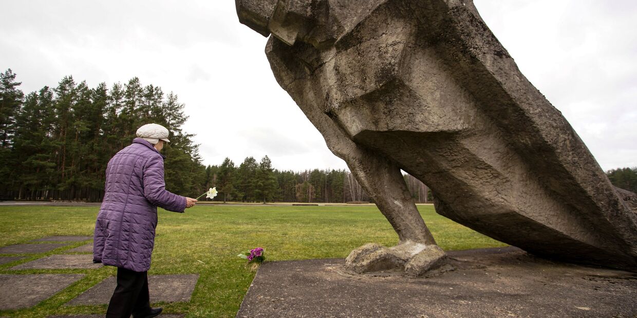 Женщина возлагает цветы к мемориалу памяти жертв фашизма на месте концлагеря Саласпилс в Латвии
