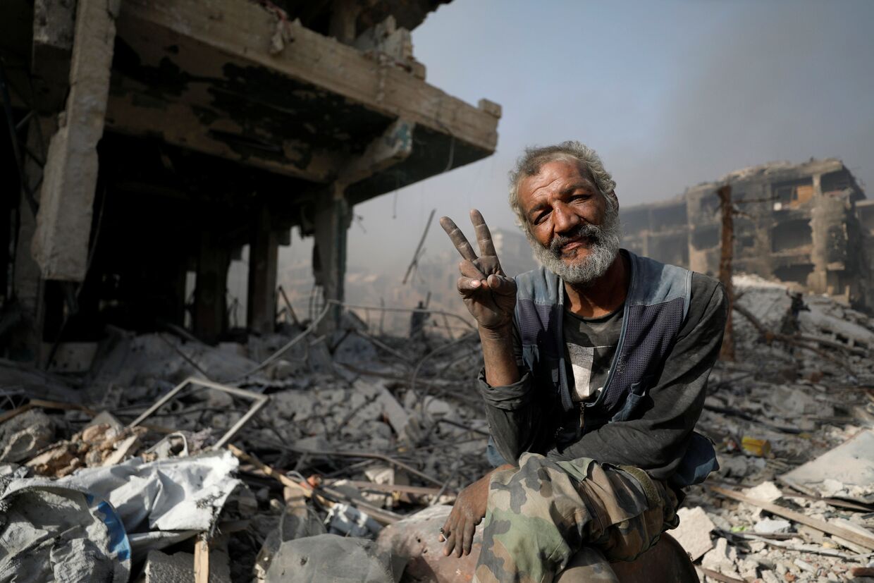 Мужчина на развалинах поврежденных зданий в Аль-Хаджар Аль-Асвад, Сирия