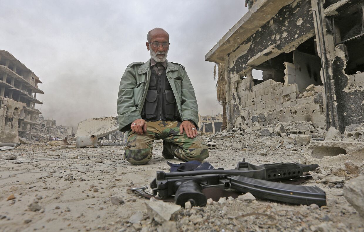 Военнослужащий на разрушенной улице в районе Хаджар Аль-Асвад на окраине столицы Дамаска