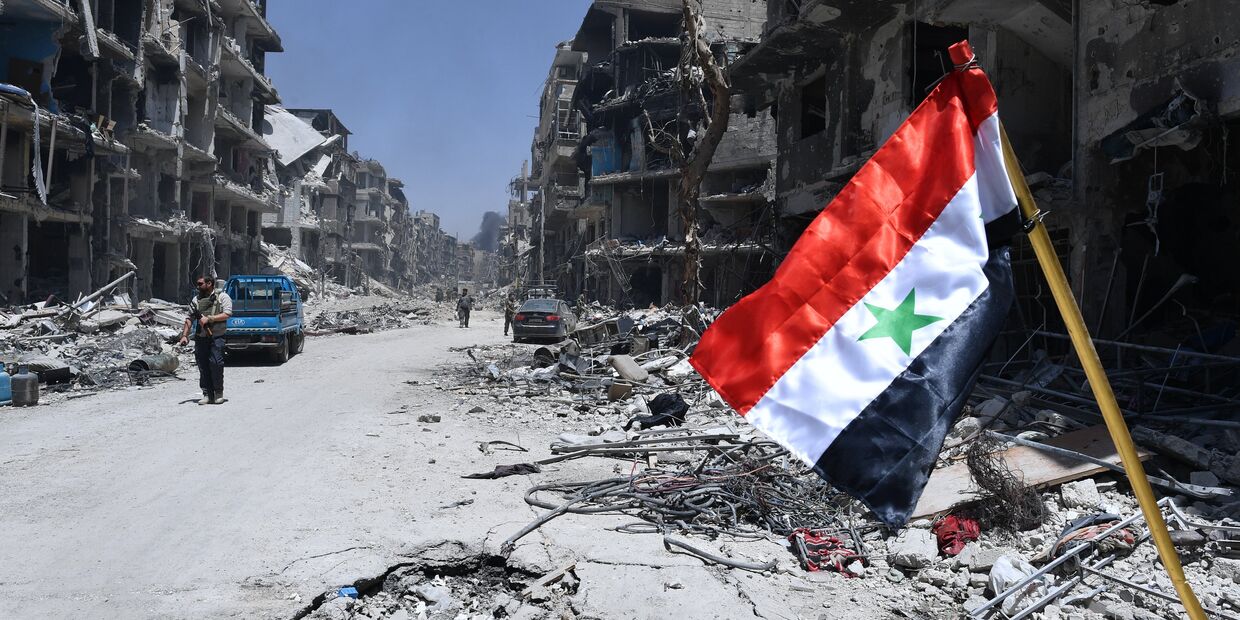 Флаг Сирии в освобожденном лагере палестинских беженцев Ярмук на юге Дамаска
