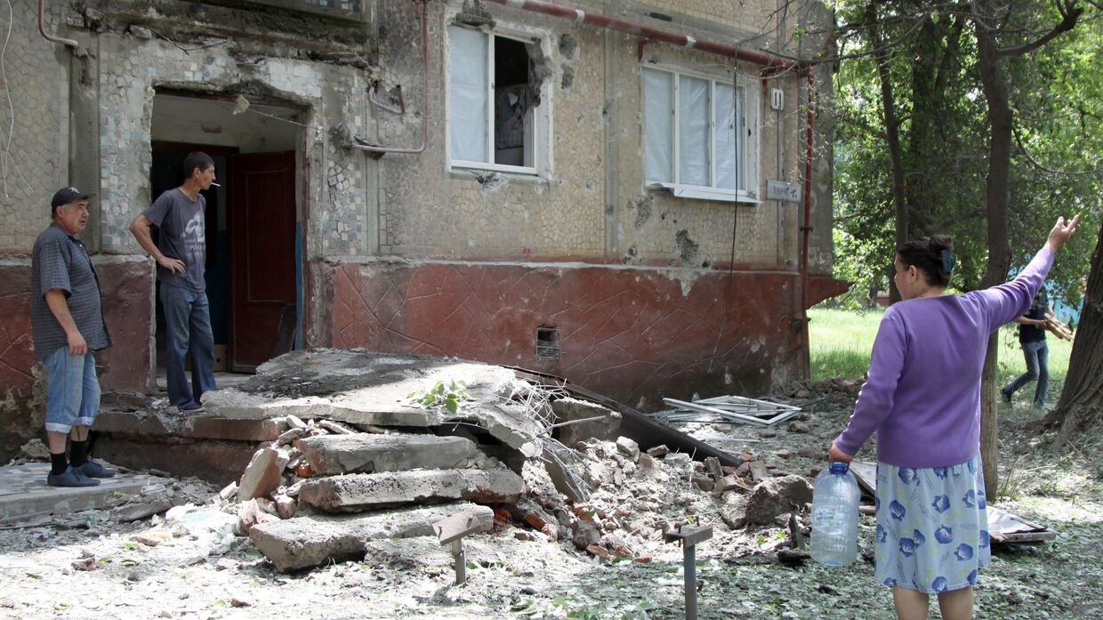 Жители во дворе жилого дома, пострадавшего в результате обстрела, в поселке Горловка Донецкой области