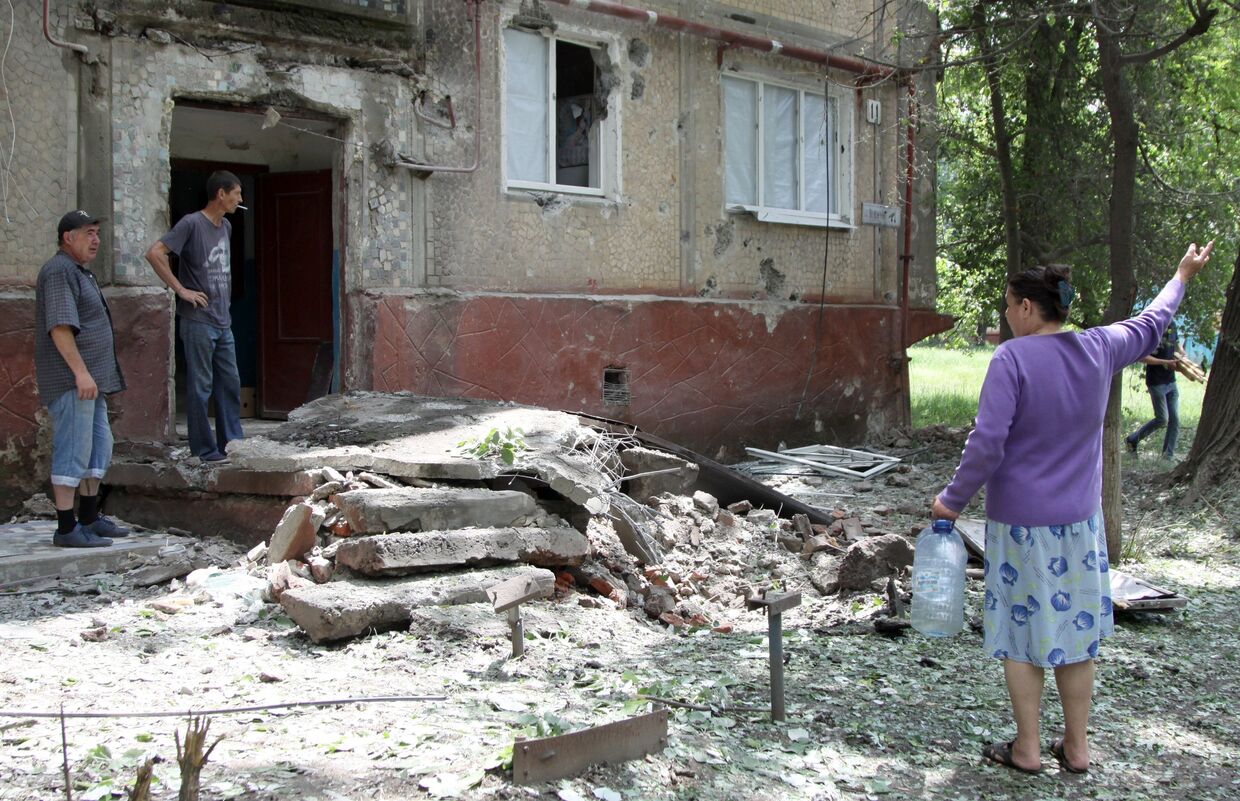 Жители во дворе жилого дома, пострадавшего в результате обстрела, в поселке Горловка Донецкой области