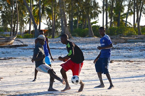 Местные жители играют в футбол на пляже в Занзибаре, Танзания