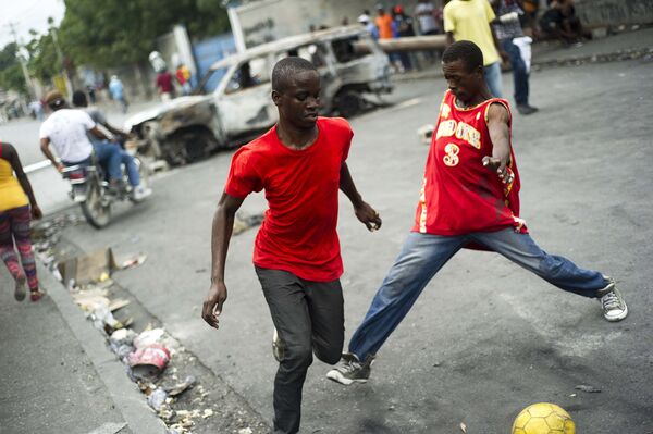 Местные жители играют в футбол на улице в Порт-о-Пренсе, Гаити