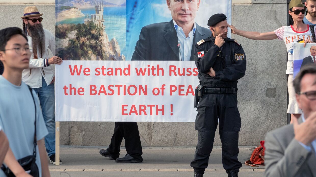 Жители Австрии держат плакат с изображением президента РФ Владимира Путина во время его встречи с федеральным президентом Австрийской Республики Александром Ван дер Белленом во дворце Хофбург в Вене