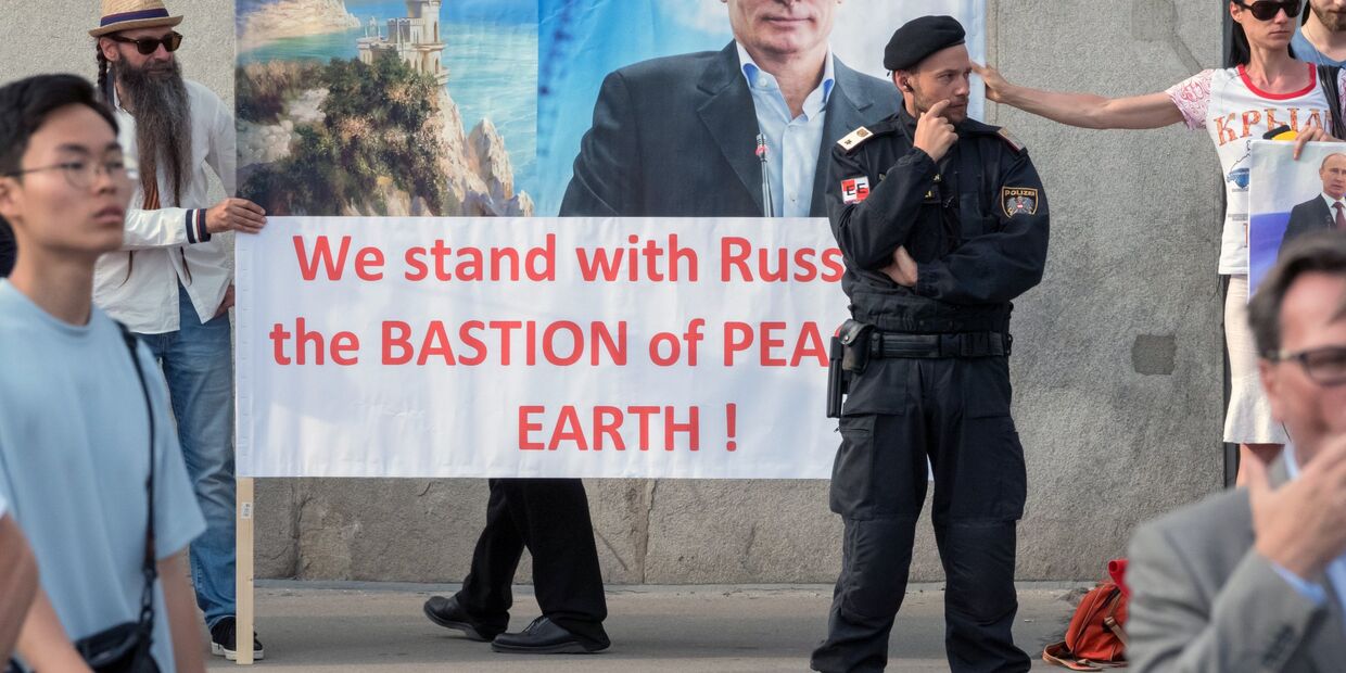Жители Австрии держат плакат с изображением президента РФ Владимира Путина во время его встречи с федеральным президентом Австрийской Республики Александром Ван дер Белленом во дворце Хофбург в Вене
