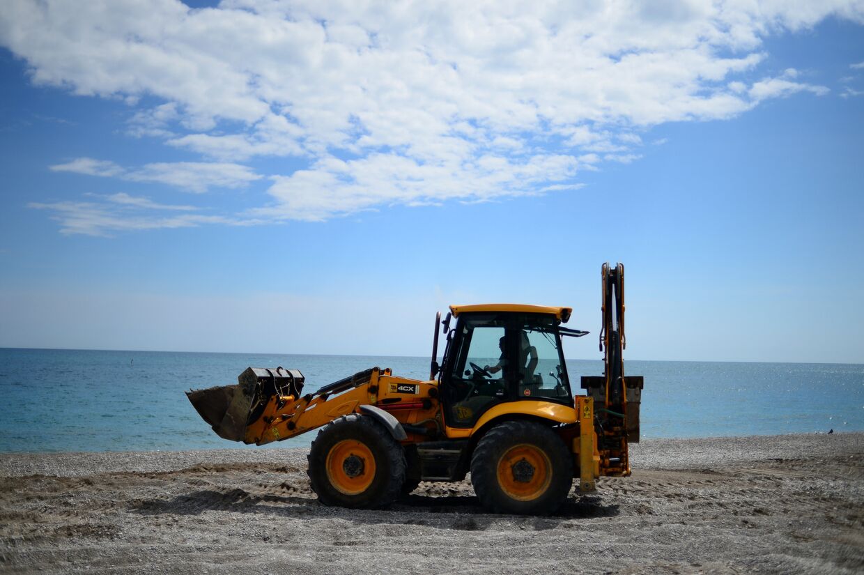 Трактор ровняет щебень на пляже в Ялте