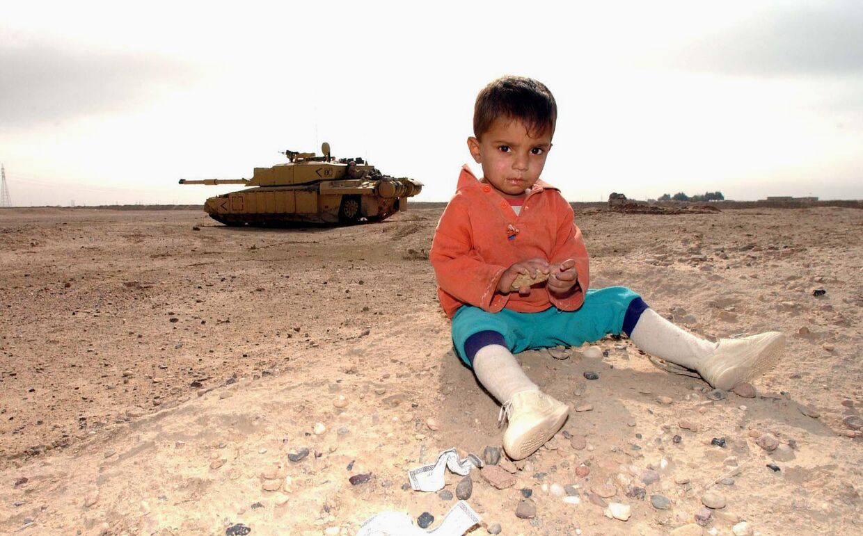 Иракский ребенок и британский танк на заднем плане недалеко от Басры
