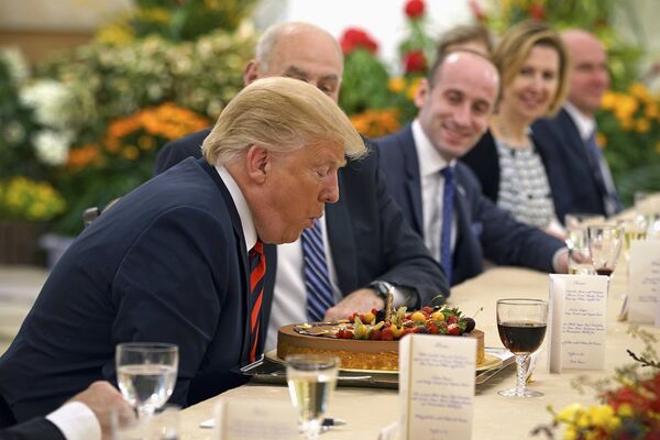 Президент США Дональд Трамп задувает свечи на торте