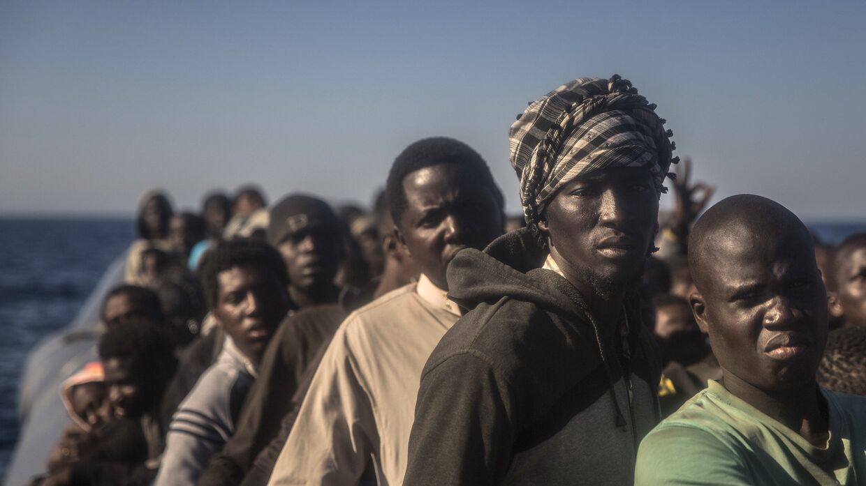 Беженцы из разных африканских стран на борту переполненного резинового катера в Ливии