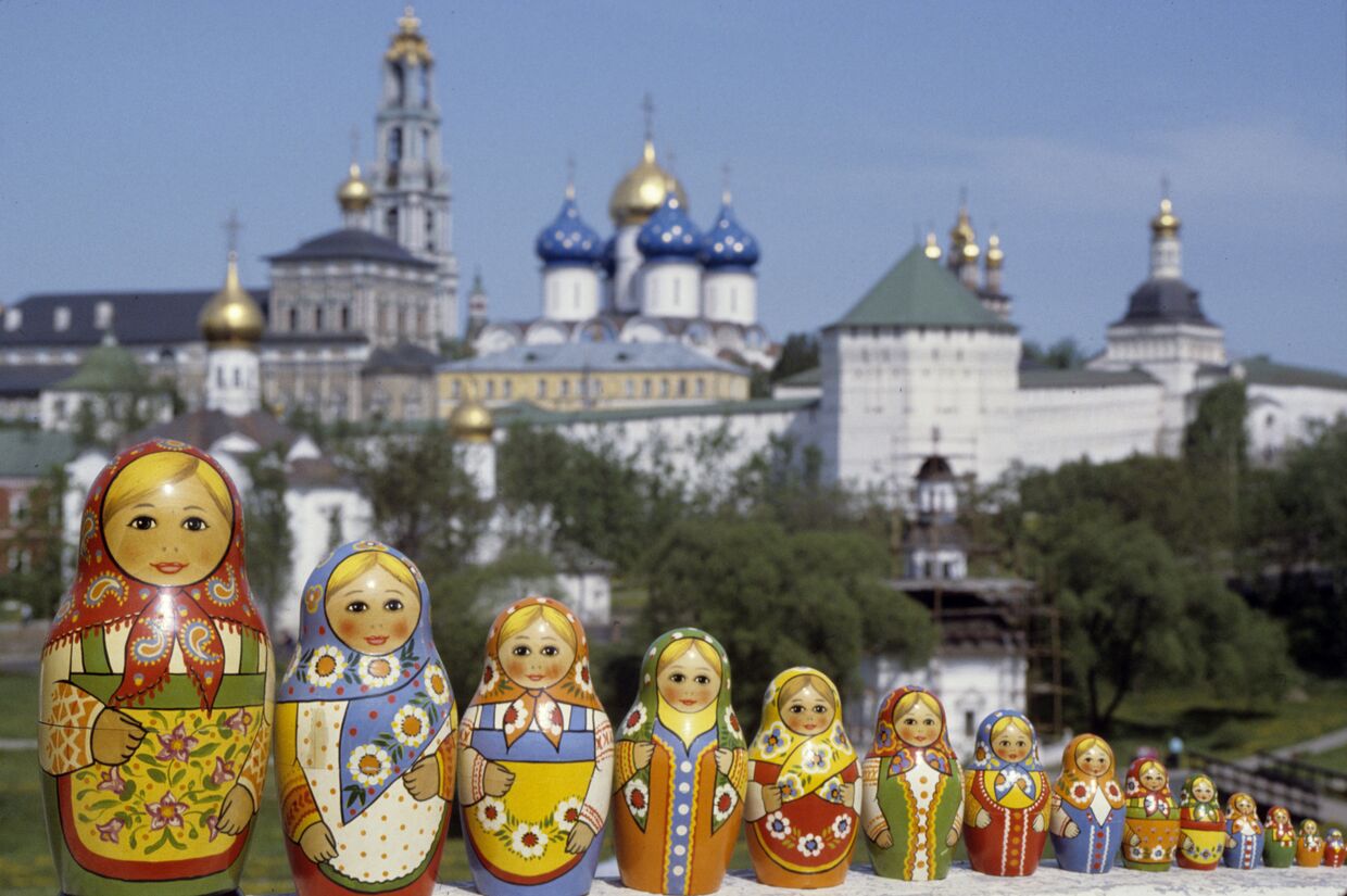 Русские матрешки, сфотографированные на фоне Троице-Сергиевой лавры