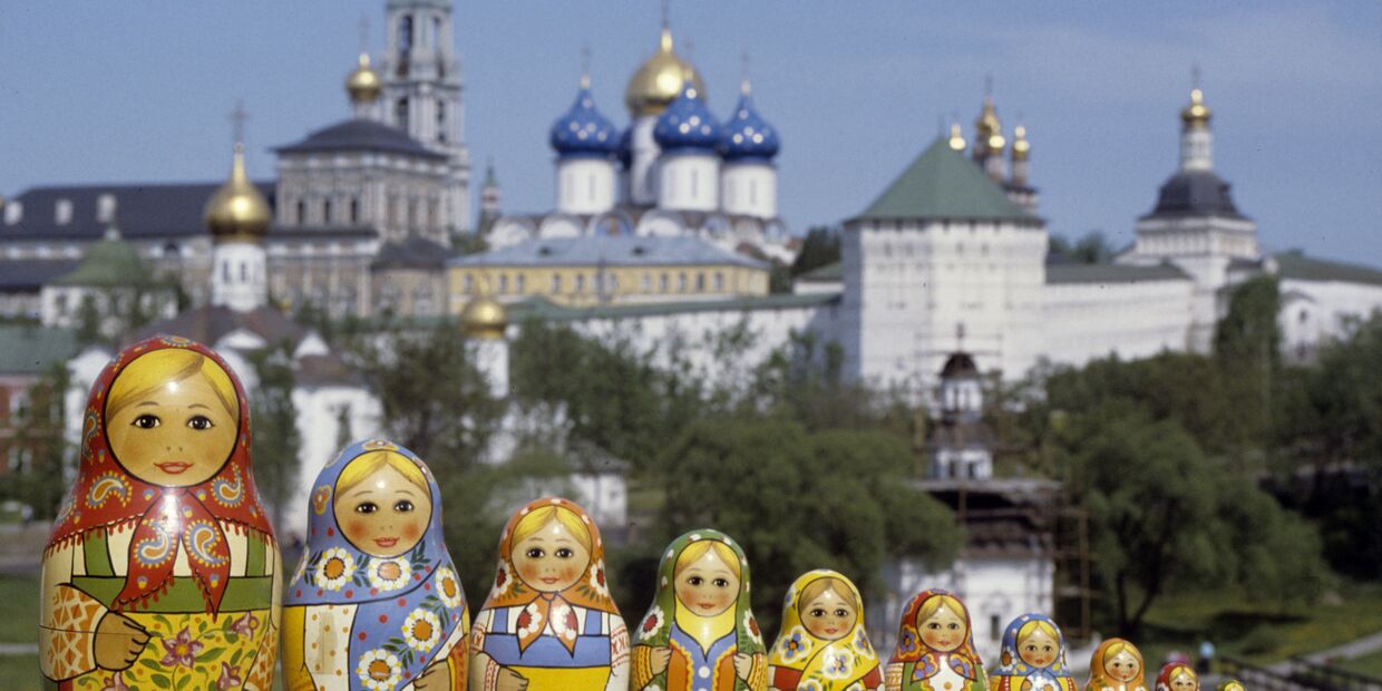 Русские матрешки, сфотографированные на фоне Троице-Сергиевой лавры