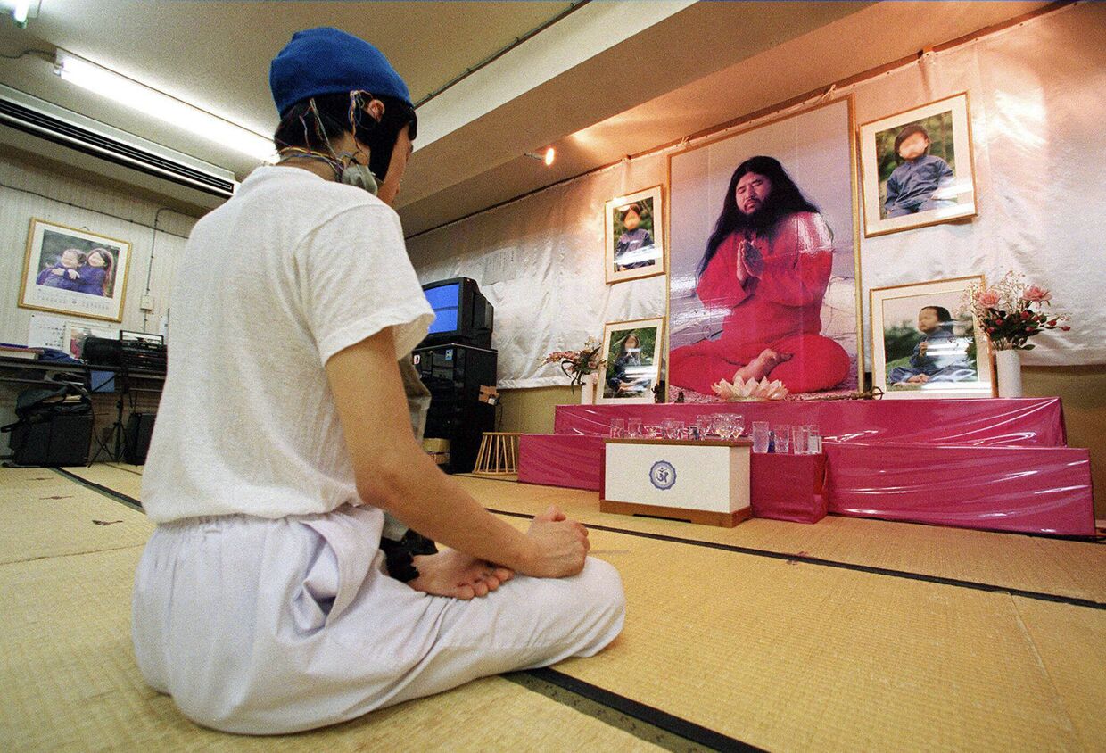 Последователь религиозной секты Аум Синрикё (террористическая организация, запрещенная в России) медитирует перед портретом Сёко Асахары в Токио
