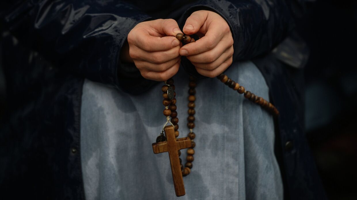 Католик молится, перебирая четки