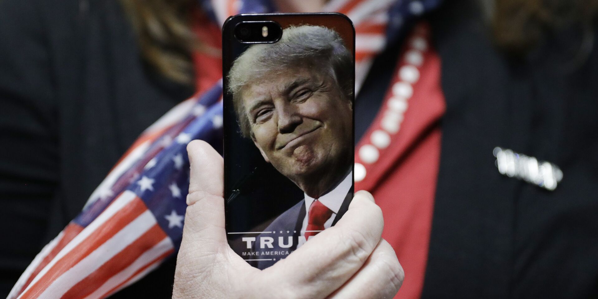 Женщина держит телефон с фотографией Дональда Трампа во время предвыборной кампании в США - ИноСМИ, 1920, 04.07.2025