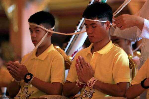 Члены футбольной команды, спасенной из пещеры в Таиланде, участвуют в религиозной церемонии
