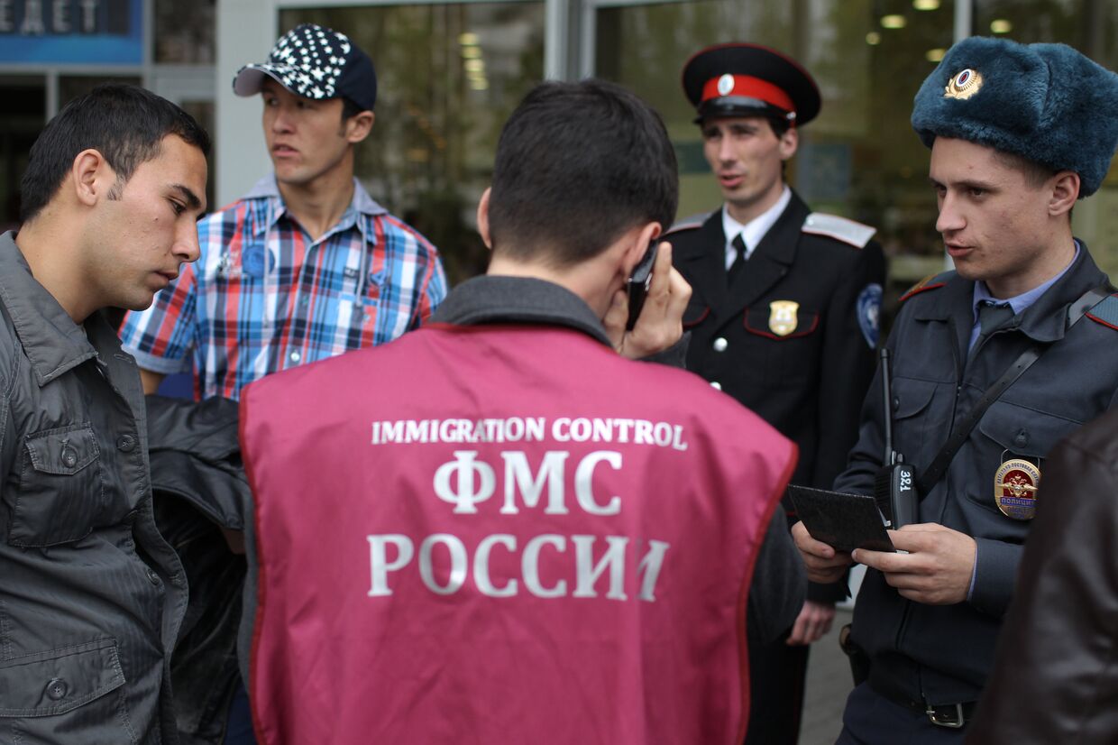 Казак, сотрудник Федеральной миграционной службы РФ и сотрудник правоохранительных органов проверяют документы во время патрулирования улиц Краснодара