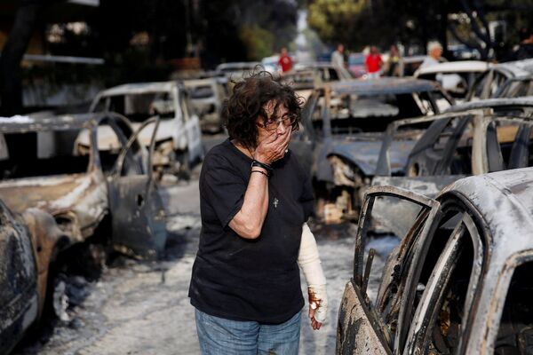 Женщина пытается найти свою собаку после разрушительного пожара в Греции
