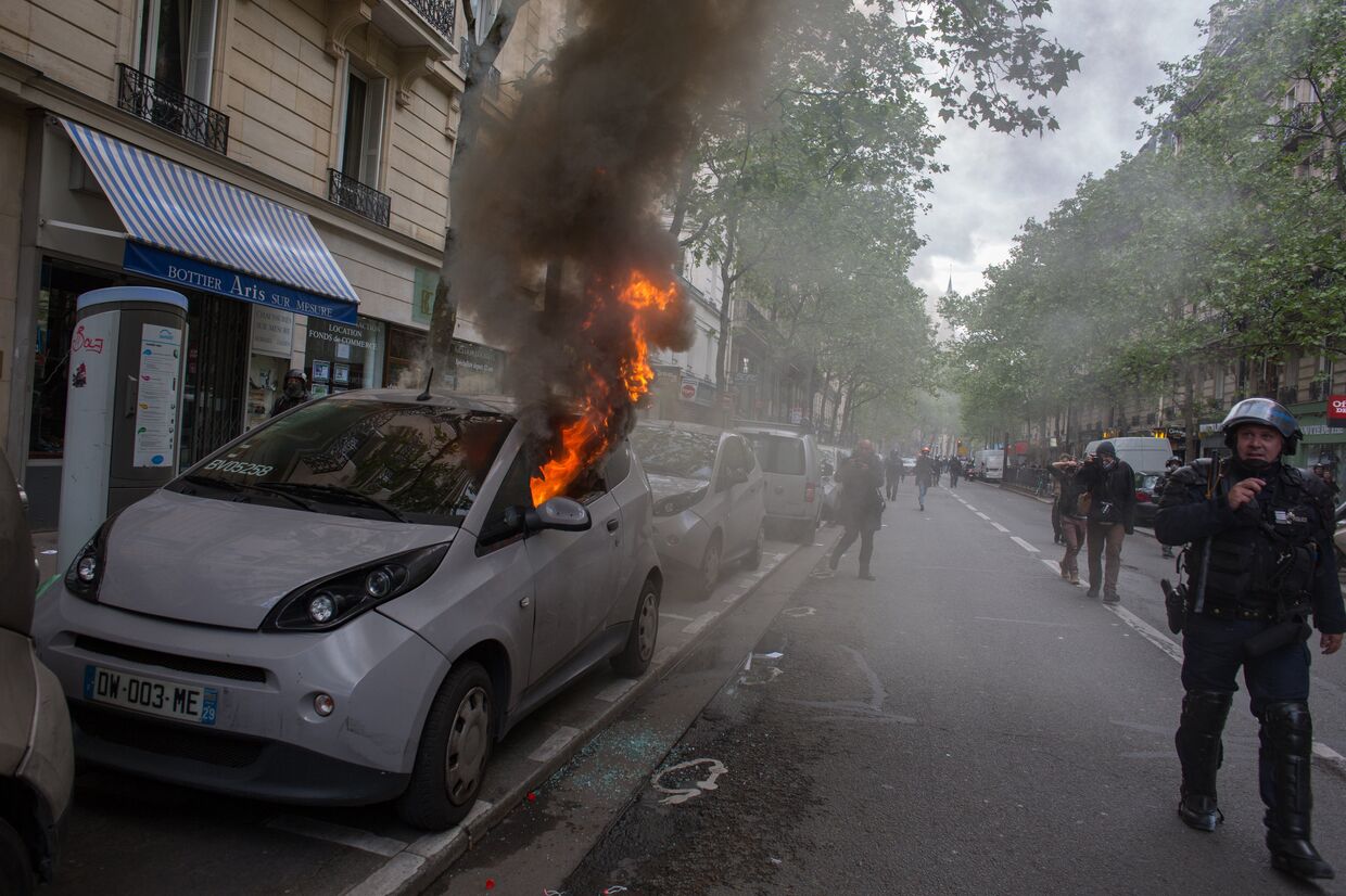 Горящий автомобиль во время беспорядков, возникших во время первомайской демонстрации в Париже