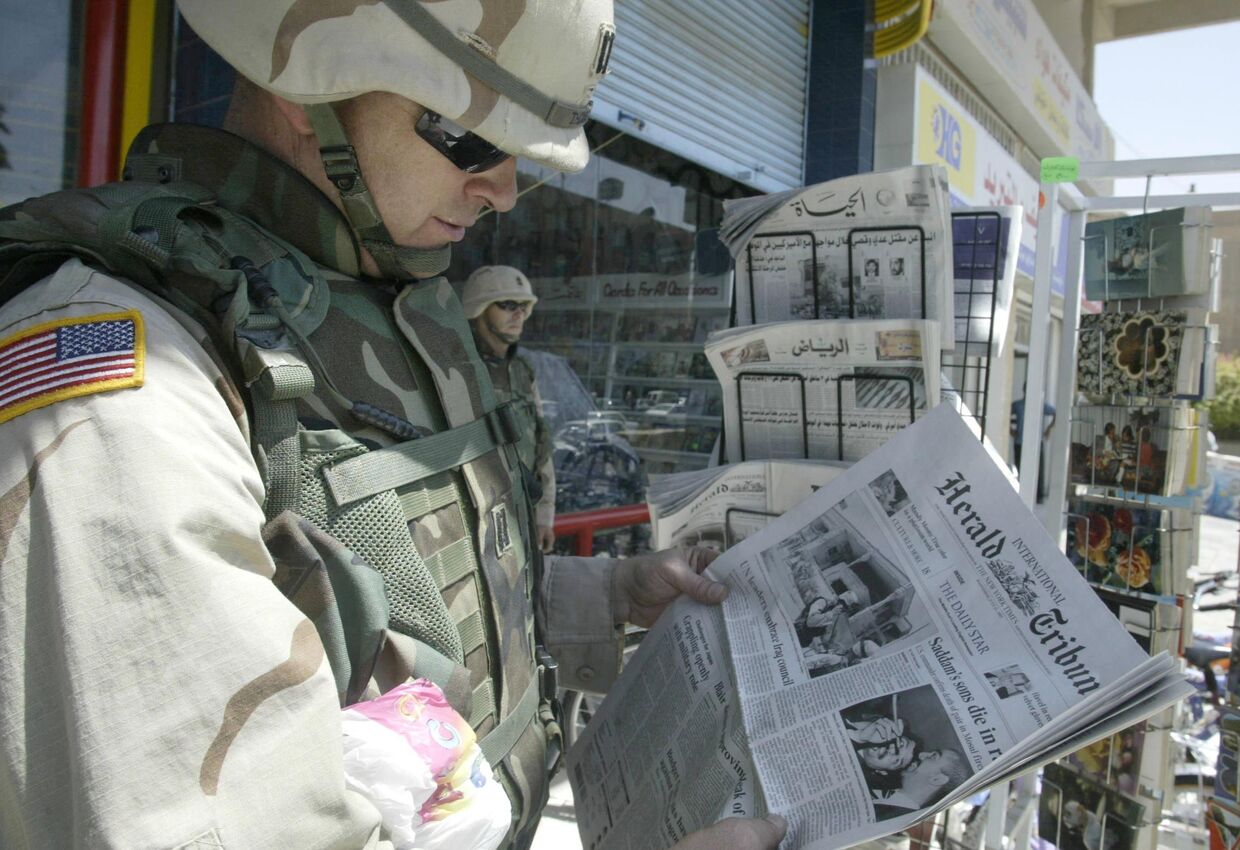 Капитан армии США Пирс Томас читает газету в Багдаде, Ирак