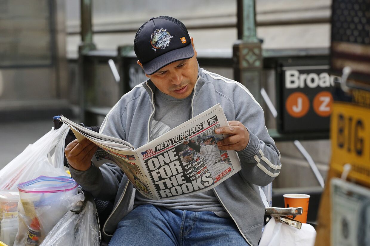 Мужчина читает газету в Нью-Йорке