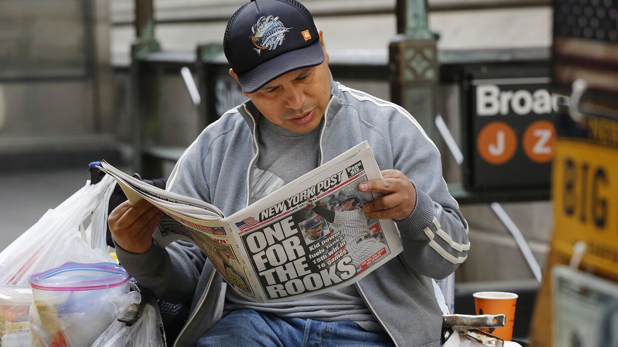 Мужчина читает газету в Нью-Йорке