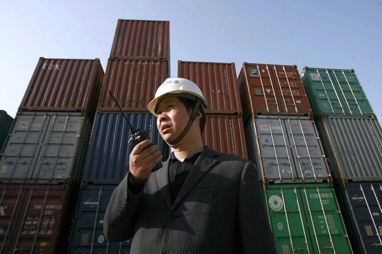 Рабочий следит за погрузкой контейнеров в порту в Ухане, Китай