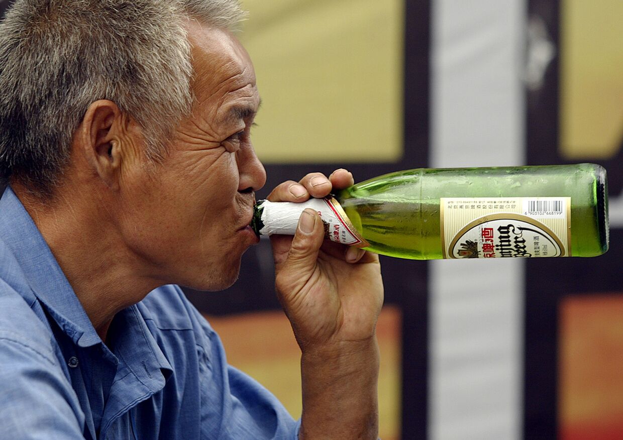 Мужчина пьет пиво в Пекине, Китай