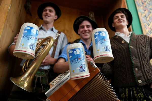 Музыканты держат официальные пивные кружки Октоберфеста в Мюнхене