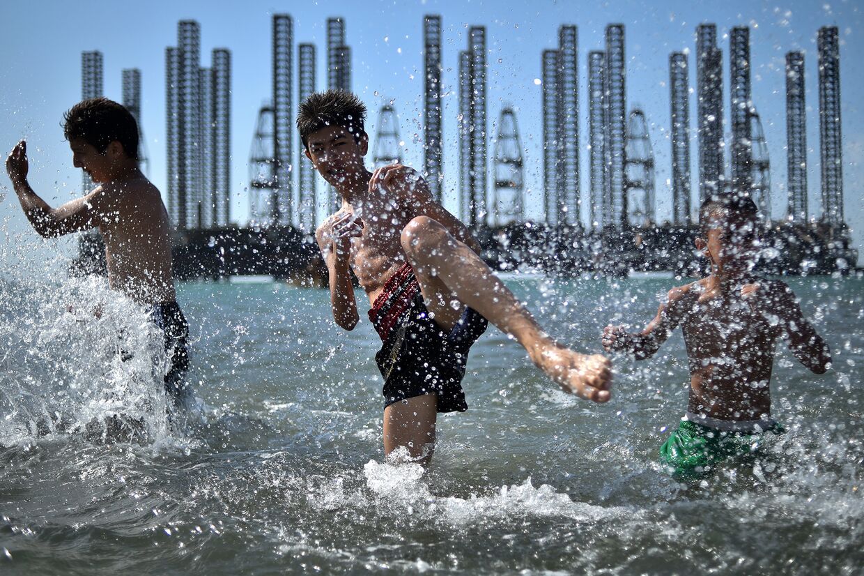 Подростки из школы бокса во время тренировки в Каспийском море у нефтяных вышек в Баку