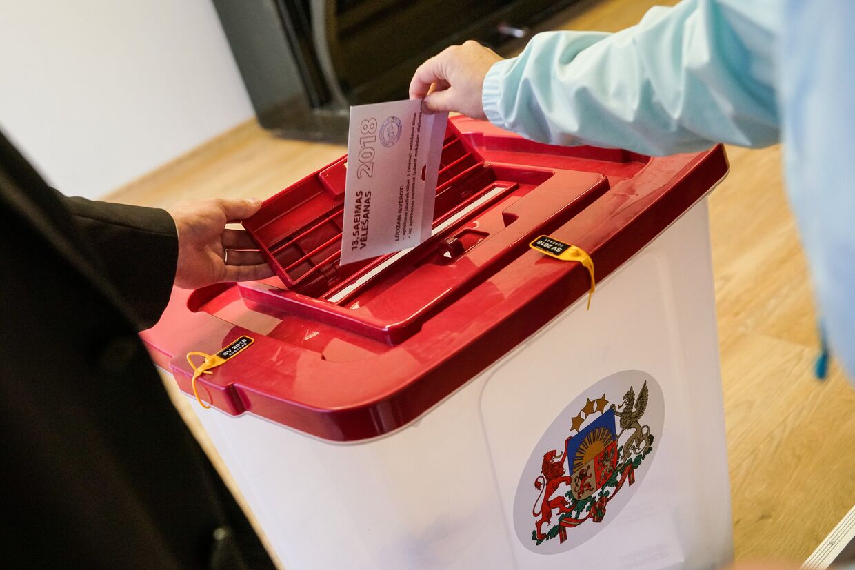 Избиратель опускает бюллетень в урну на избирательном участке 678 в Огре во время парламентских выборов в 13-й Сейм Латвии. 6 октября 2018