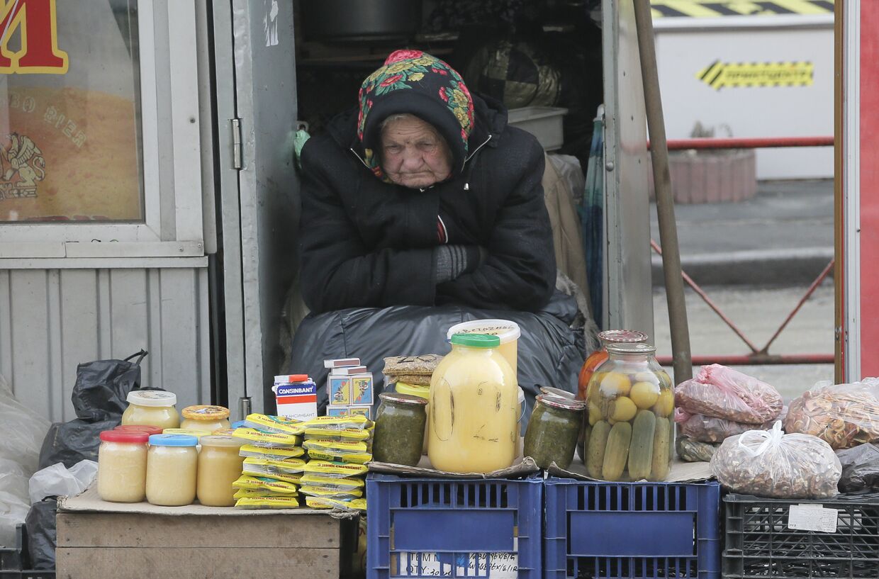 Пожилая женщина торгует на улице в Киеве