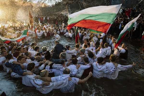 Верующие танцуют в холодных водах реки Тунджа во время дня Богоявления в городе Калофер, Болгария