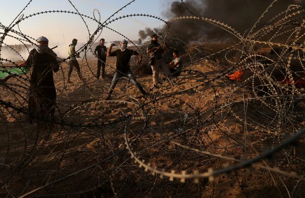 Палестинцы бросают камни в израильские войска во время протеста