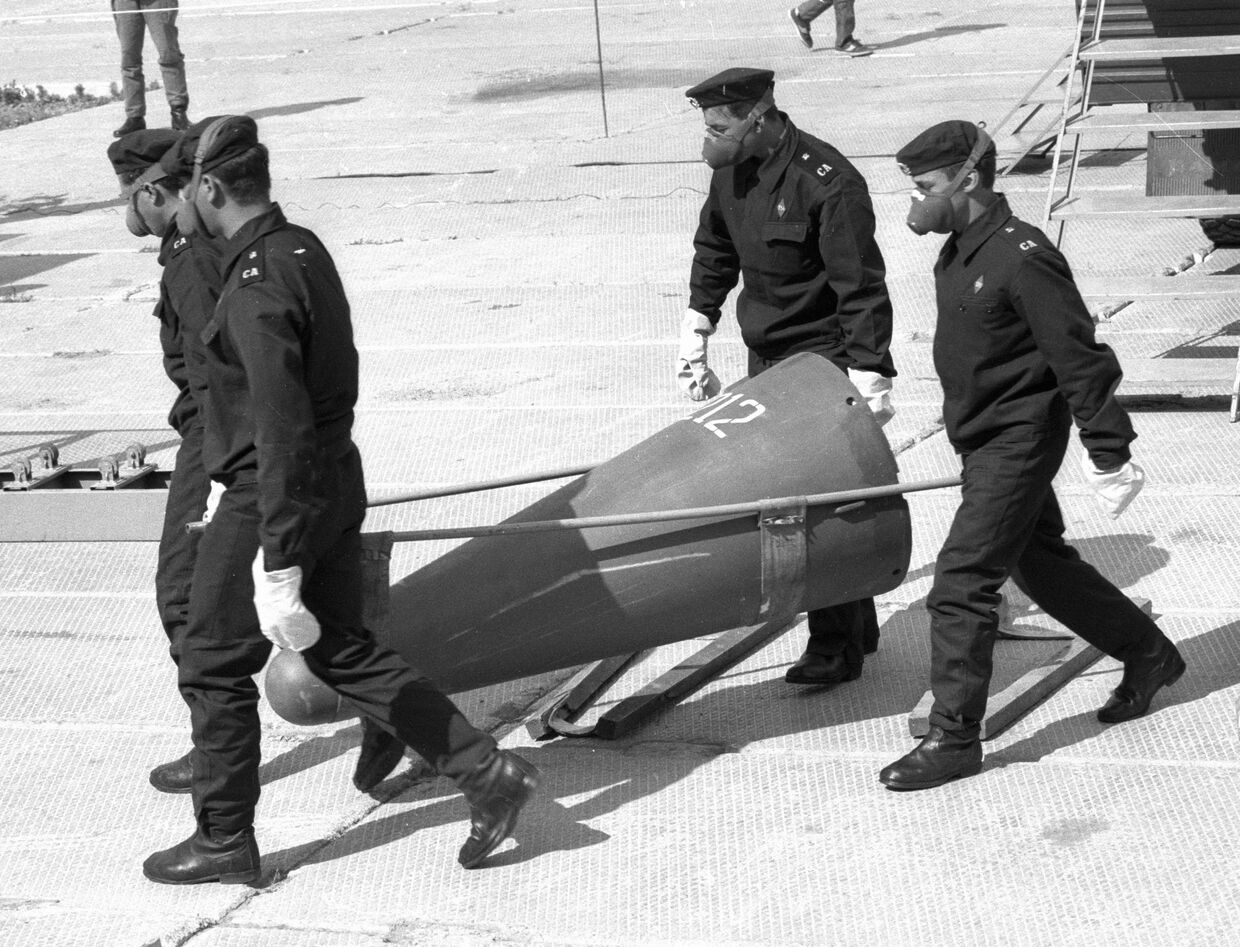 Технические специалисты несут головную часть снятой с боевого дежурства ракеты РСД-10