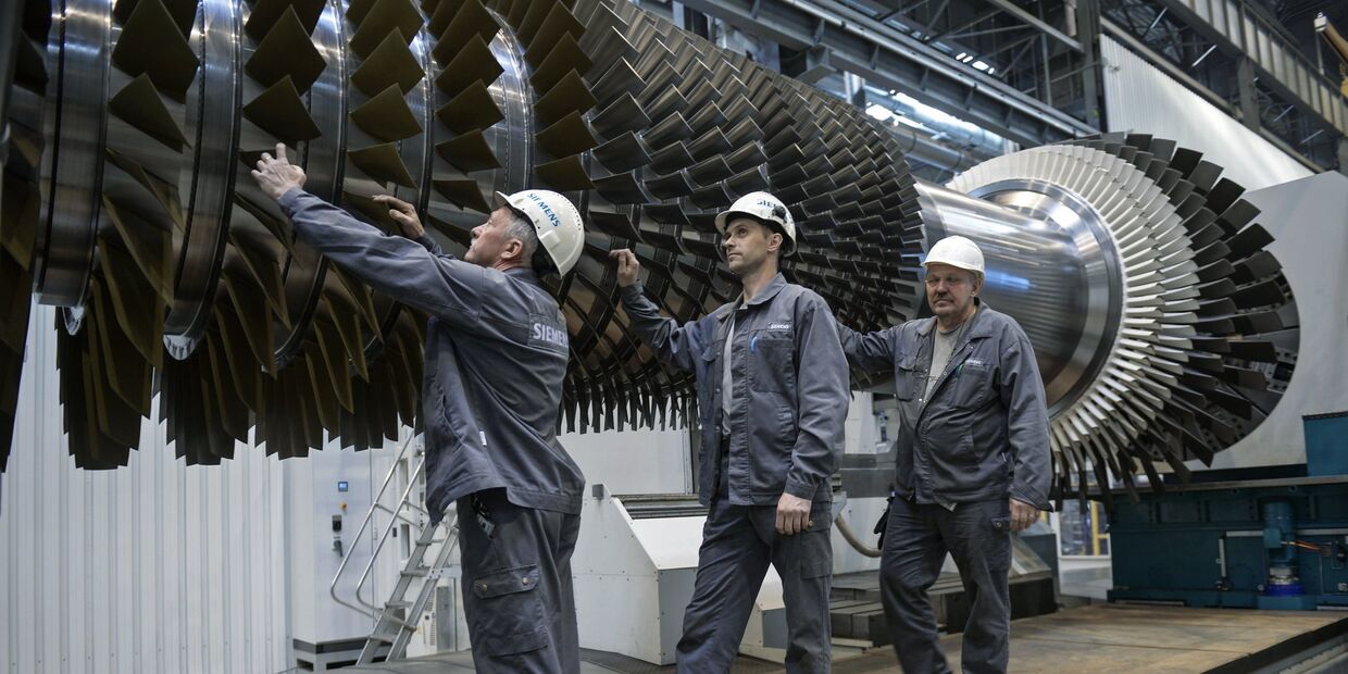 Рабочие ООО Сименс технологии газовых турбин осматривают ротор с лопатками в цехе по восстановлению лопаток газовых турбин