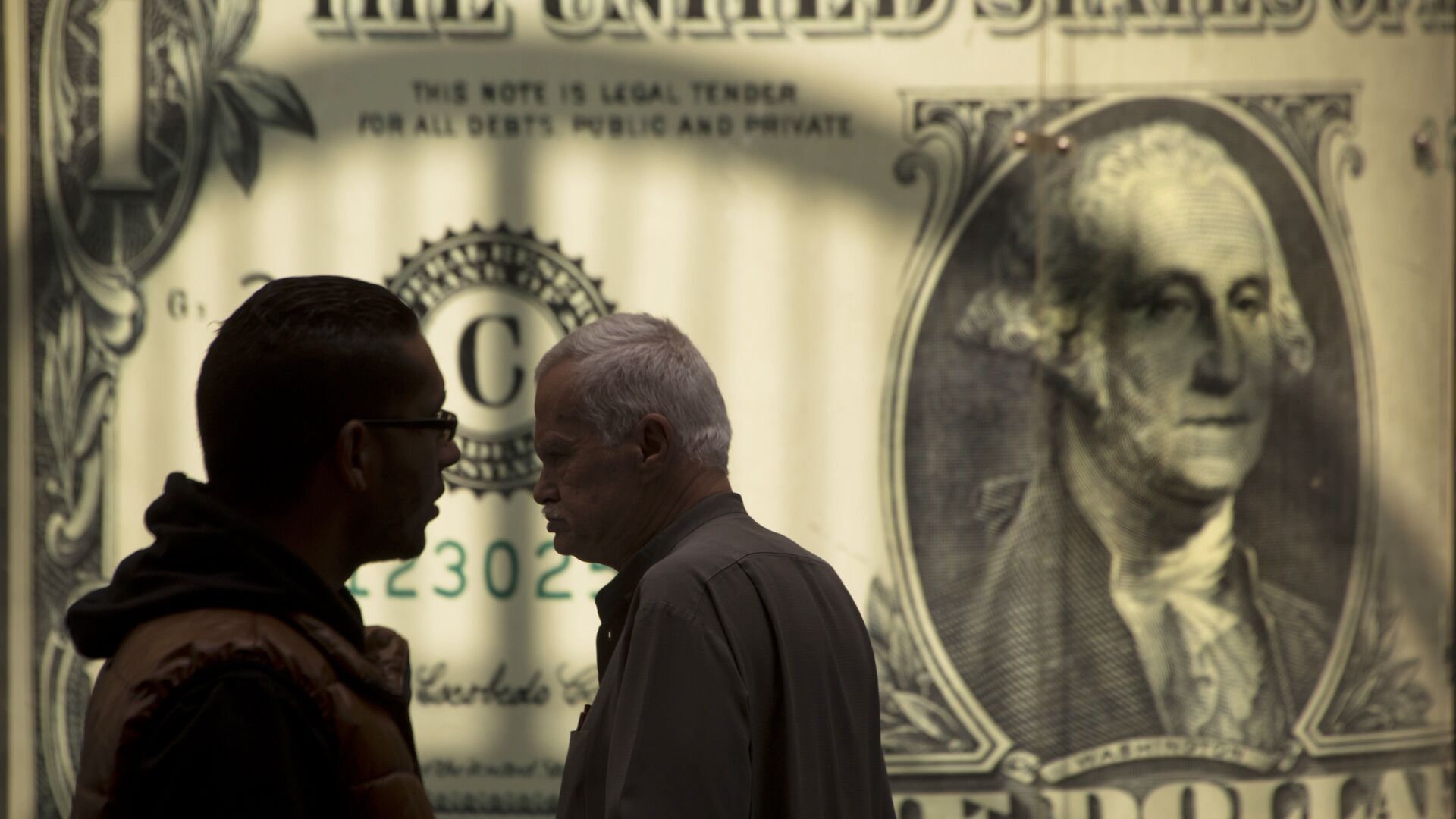 Мужчины у баннера с изображением американского доллара возле обменного пункта - ИноСМИ, 1920, 17.07.2023