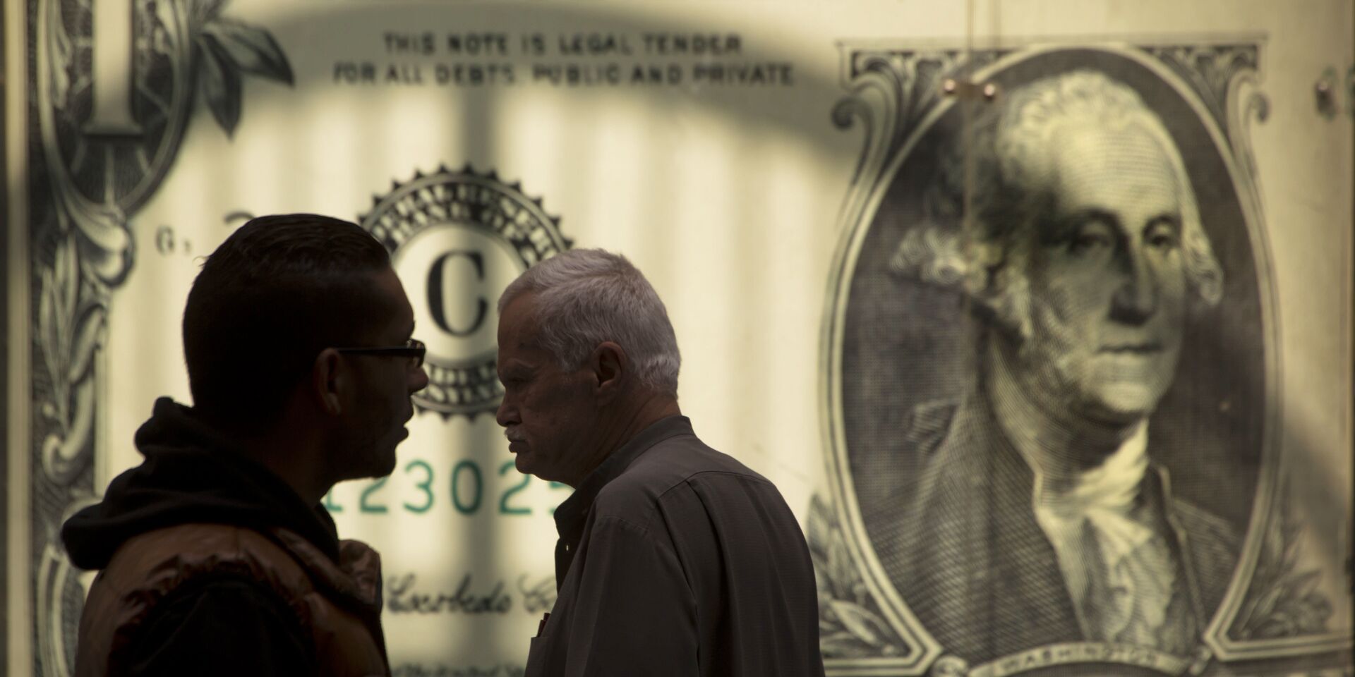 Мужчины возле баннера с изображением американского доллара возле обменного пункта - ИноСМИ, 1920, 23.12.2020