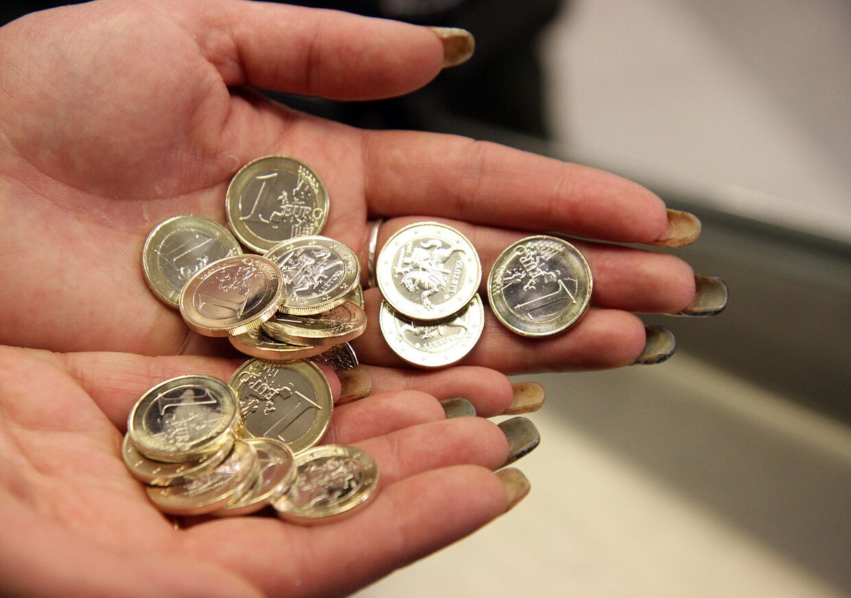 Кассир считает монеты в вильнюсском супермаркете в Литве