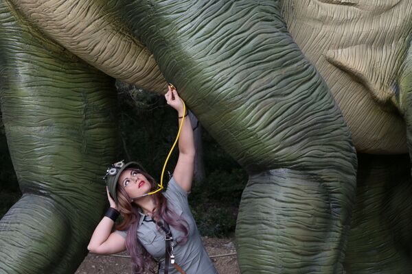 Косплеер позирует с моделью динозавра в натуральную величину на выставке в ботаническом саду в Крыму