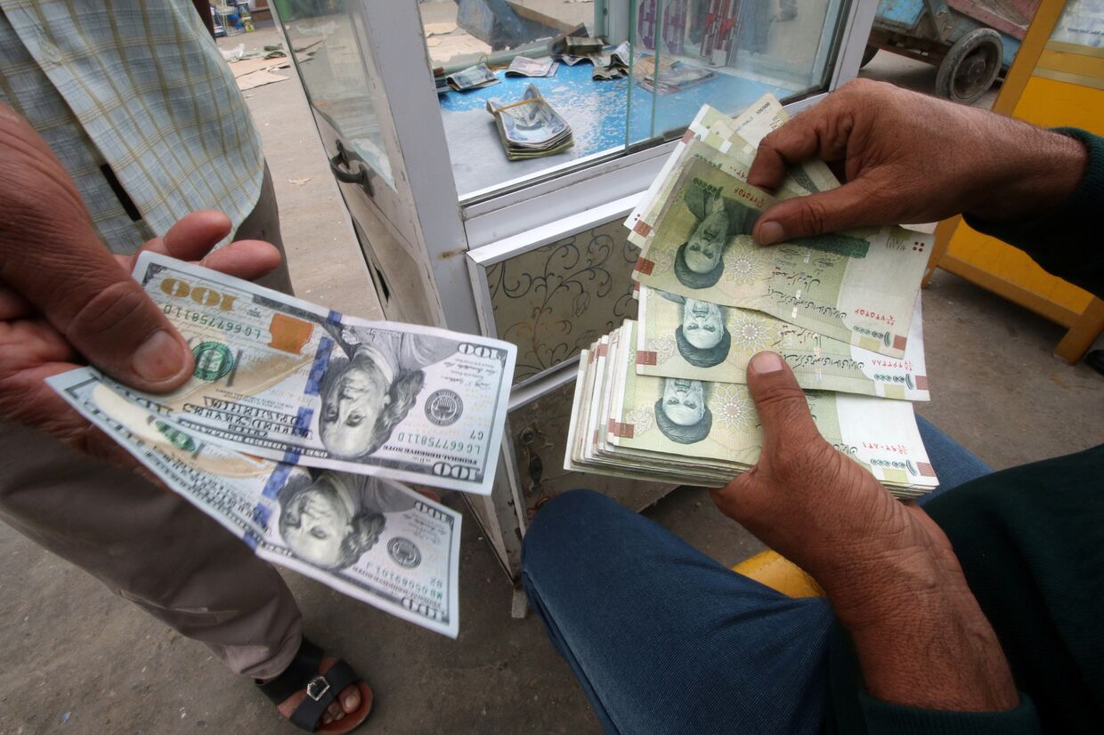 Иранские риалы и доллары США в пункте обмена валюты в Басре, Ирак