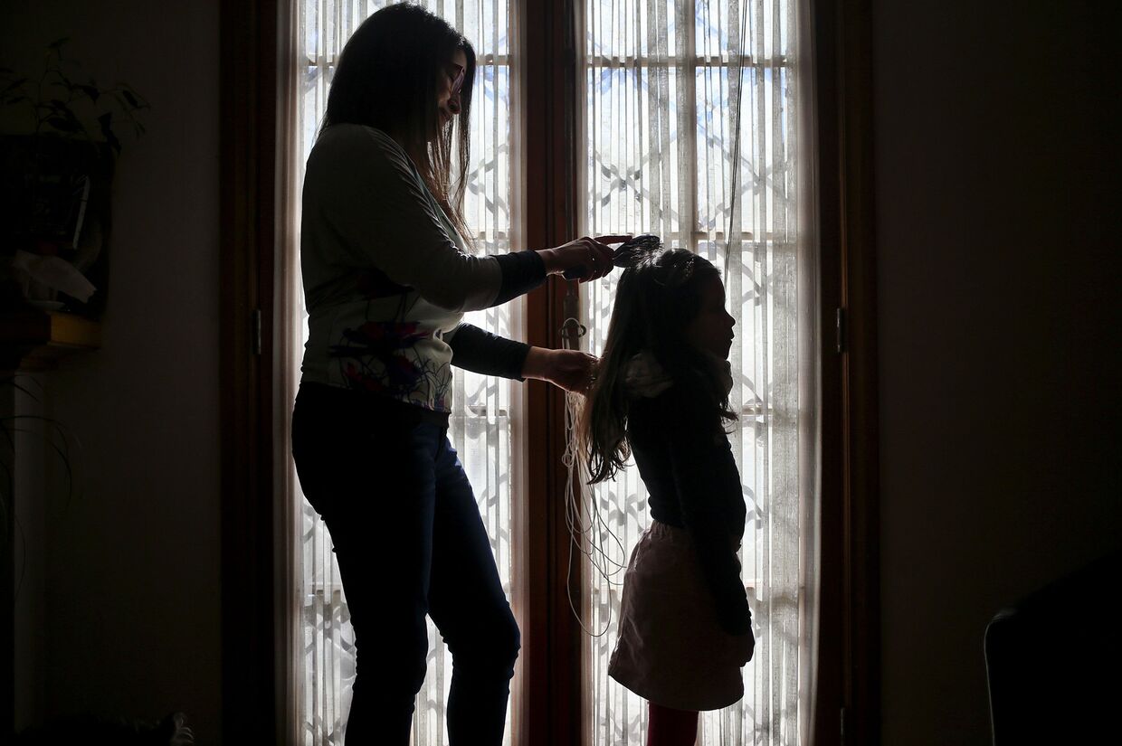 Моника Флорес расчесывает волосы ребенку-трансгендеру у себя дома в Сантьяго